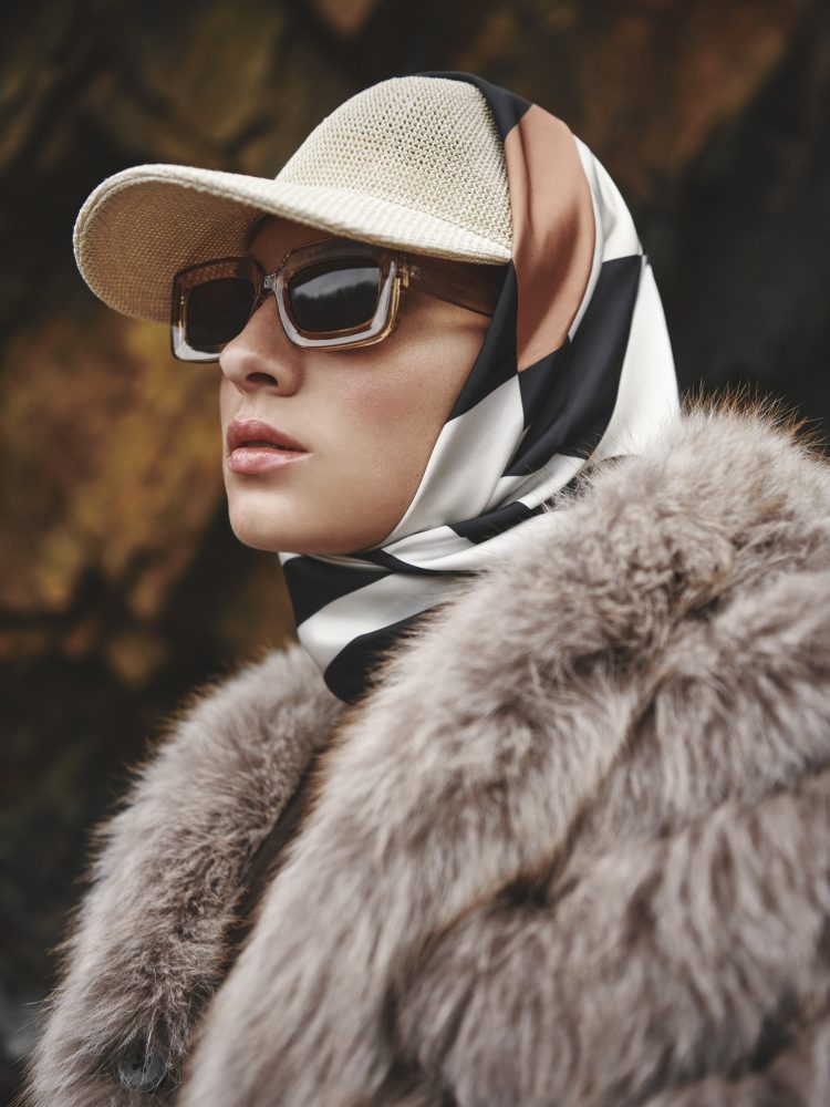Asociación Española de Peletería SFA - Primer plano de una mujer vestida con una abrigo de piel natural y una gorra, un pañuelo y unas gafas de sol.